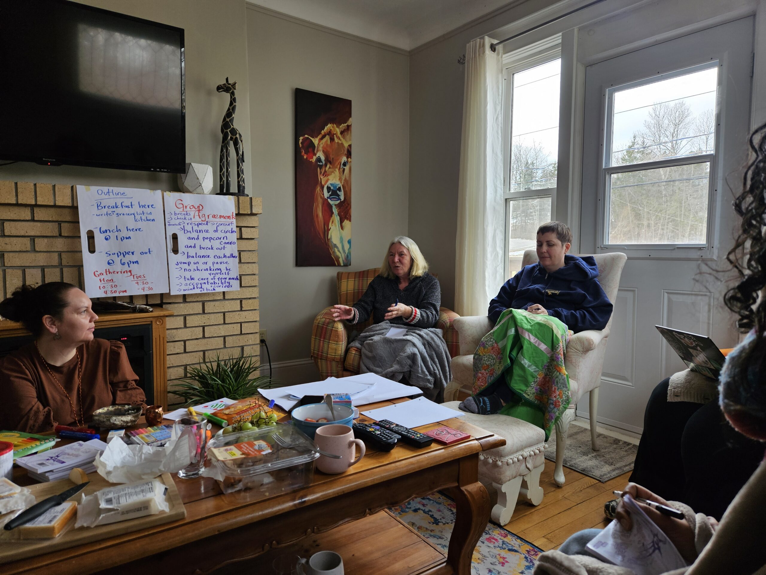 Photo of three women engaged in conversation in a bright living room