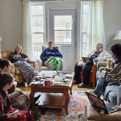 A group of women talking in circle in a bright, cosy living space.
