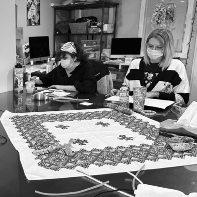 Black and white photo of two women in medical masks working at a table