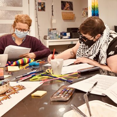 Colour photograph of two women in medical masks working at a table
