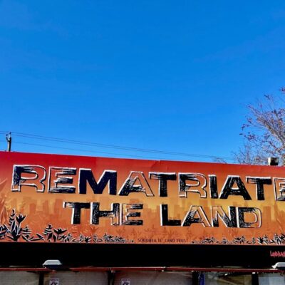 A billboard banner by the Sogorea Te Land Trust that reads "Rematriate the Land"