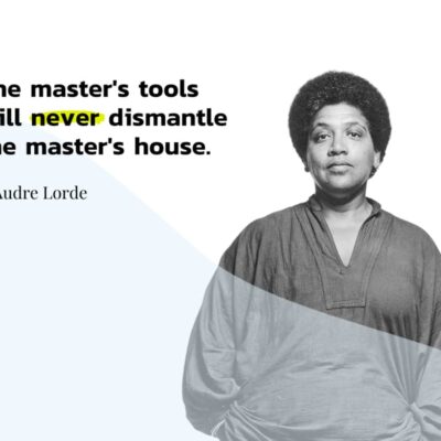 A black and white image of Audre Lorde, a Black woman with natural hair in a loose, long-sleeved blouse. Her hands are in her pockets. Next to her is text that reads “The master’s tools will never dismantle the master’s house.”