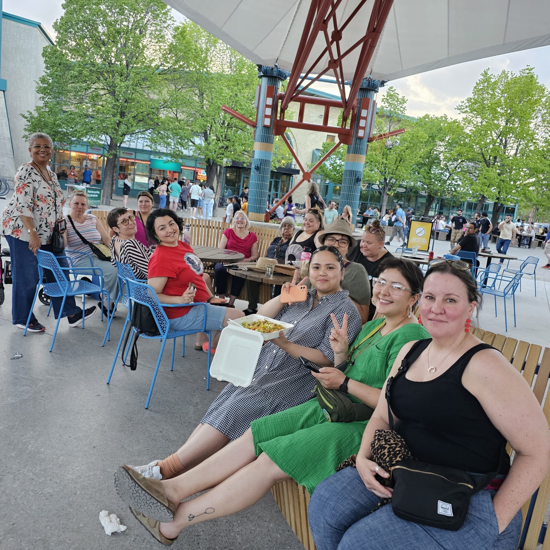 A group of people seated outdoors on benches and tables