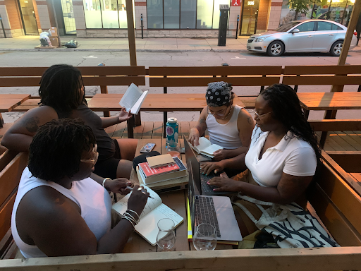 A photo of four women gathered around a table outside